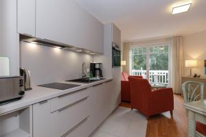 a kitchen with white cabinets and red chairs in a room at Ferienwohnungen am Strand - Strandvilla Belvedere in Kühlungsborn