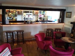 un bar con sillas rosas y barra de bar en The Sibson Inn Hotel, en Water Newton