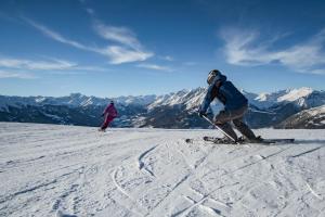 two people are skiing down a snow covered mountain at Bergerhof in Kals am Großglockner