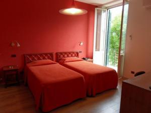 two beds in a room with red walls and a window at Hotel Villa Archirafi in Palermo