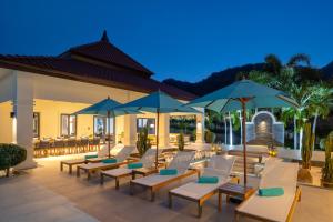 - une terrasse avec des chaises et des parasols la nuit dans l'établissement Ultimate Luxury Bali Style Villa with 5 Bedrooms! B11, à Hua Hin