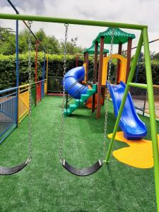 een speeltuin met drie schommels en een glijbaan bij Apartamentos Ecologic PARK - Caldas Novas in Caldas Novas