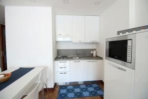 uma cozinha branca com um lavatório e um micro-ondas em Casa Vacanze Finestra del Pescatore em Marone