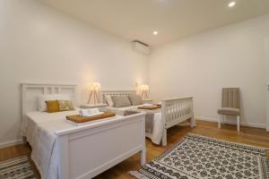 a white bedroom with a bed and a crib at Janela Mar Garden in Lagoa