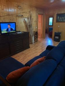 uma sala de estar com um sofá azul e uma televisão em casa peninsula caspe 2 em Caspe