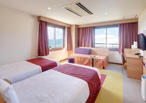 a hotel room with two beds and a desk at Hotel Yugaf Inn Okinawa in Nago