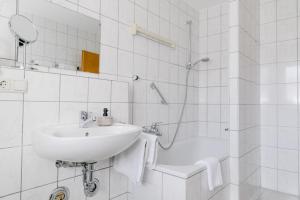 a white bathroom with a sink and a shower at Hotel Vogtareuther-Hof in Vogtareuth +96 photos