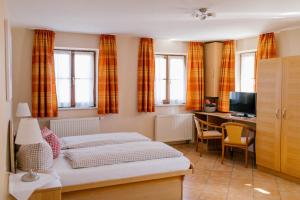 a bedroom with two beds and a desk with a computer at Hotel Vogtareuther-Hof in Vogtareuth