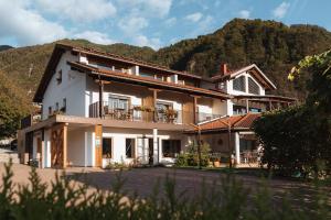 ein großes weißes Haus mit einem Berg im Hintergrund in der Unterkunft Hotel Penzion Kobala in Tolmin