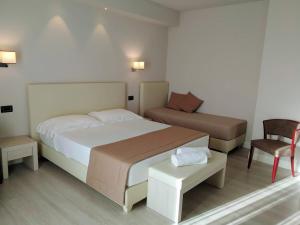 a hotel room with two beds and a chair at Hotel Villa Barsanti in Marina di Pietrasanta