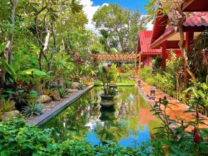 un jardín con un estanque frente a una casa en Ruenkanok Thaihouse Resort, en Hua Hin