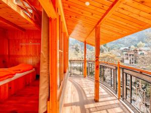 a room with a balcony with a bed and a view at Madpackers Jibhi - Of Streamsides & Waterfalls in Jibhi