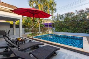 uma piscina com um guarda-sol vermelho e cadeiras em Honeybee Pool Villa Smooth as Silk em Praia de Aonang