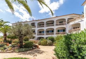 a large white building with trees and bushes at Apartment Buena Vista in Cala Santanyi