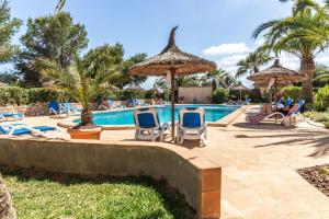 a pool at a resort with chairs and palm trees at Apartment Buena Vista in Cala Santanyi