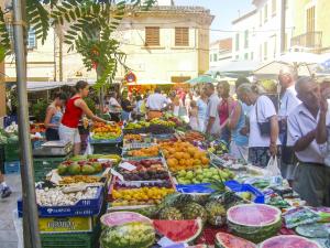 a group of people standing around a market with fruits and vegetables at Apartment Buena Vista in Cala Santanyi