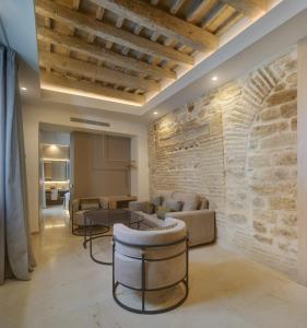 ein Wohnzimmer mit einer Steinmauer und Möbeln in der Unterkunft Apartamentos Los Patios del Pañuelo in Córdoba