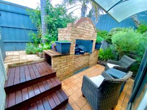 a backyard patio with a brick fireplace and chairs at River cottage in Blairgowrie