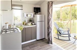 a kitchen with a refrigerator and a table and a chair at Camping Paris Beau Village in Villiers-sur-Orge