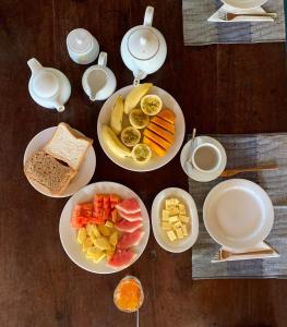 a table with plates of food and bowls of fruit at Green Escape Unawatuna in Unawatuna