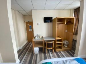 ein Zimmer mit einem kleinen Schreibtisch und einem kleinen Schrank in der Unterkunft Cardiff Sandringham Hotel in Cardiff