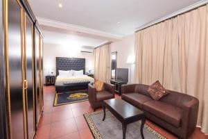 a hotel room with a bed and a couch and chair at Oak Haven Hotel & Suites in Port Harcourt