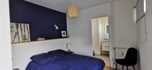 um quarto com uma cama azul e uma cadeira preta em Centre Reims Cathédrale avec balcon em Reims