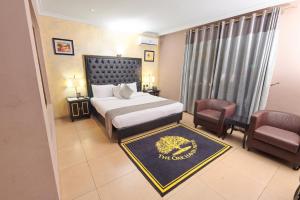 a hotel room with a bed and a chair at Oak Haven Hotel & Suites in Port Harcourt
