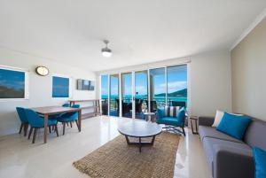 a living room with a couch and a table and chairs at The Sebel Whitsundays in Airlie Beach