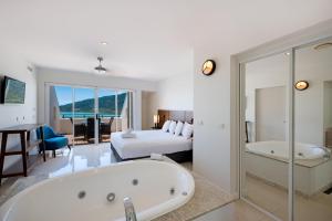 een grote badkamer met een bad en een slaapkamer bij The Sebel Whitsundays in Airlie Beach