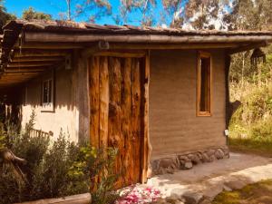 una casa antigua con una puerta de madera en un jardín en El Tio Hostal, en Otavalo