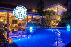 a swimming pool in front of a hotel at night at Baan Sawan Samui Resort in Chaweng Noi Beach