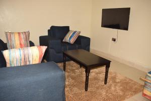 sala de estar con sofá, mesa y TV en Stylish 2BR with Wi-Fi and secure parking, en Kakamega