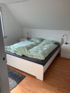 a bed in a bedroom with a white wall at Centrum lejlighed in Viborg