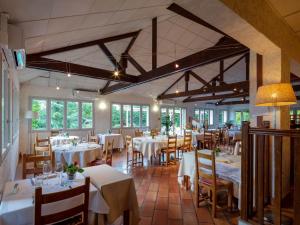 een restaurant met witte tafels, stoelen en ramen bij Logis Noemys Morgon in Villié-Morgon