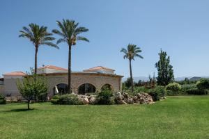 a house with palm trees in front of a yard at Caldera Platanias Villas in Platanias