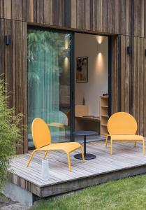 2 gelbe Stühle und ein Tisch auf einer Holzterrasse in der Unterkunft Salty Woods Lodge, Chambre d'hôtes in Vieux-Boucau-les-Bains