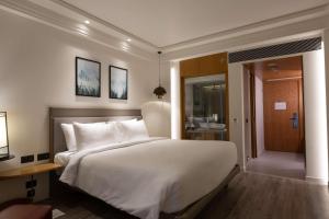 1 dormitorio con 1 cama blanca grande y baño en The Oasis Mussoorie - A Member of Radisson Individuals, en Mussoorie