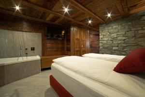 sypialnia z 2 łóżkami i kamienną ścianą w obiekcie Café Quinson Relais de Charme w mieście Morgex