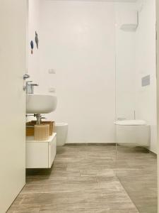 La salle de bains blanche est pourvue d'un lavabo et de toilettes. dans l'établissement Casa Claudio, à Nago-Torbole