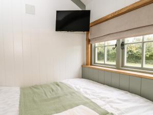 um quarto com uma cama e uma televisão de ecrã plano em Jasmine Hut, Myrtle Farm em Bristol