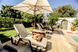 eine Gruppe Stühle und ein Sonnenschirm neben einem Pool in der Unterkunft Appartamento ellea resort in San Michele Salentino