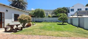 a backyard with a picnic table in the grass at Normandie On Sea in Hermanus