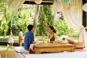a man and a woman sitting at a table at Anantara Bophut Koh Samui Resort in Bophut
