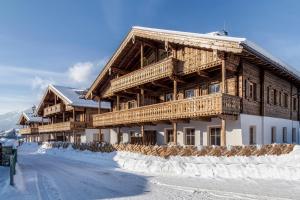 un grand bâtiment en bois avec de la neige au sol dans l'établissement Alpin Residenzen Panoramabahn by Alpina-Holiday, à Hollersbach im Pinzgau