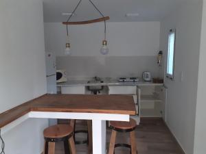 una pequeña cocina con mesa de madera y taburetes en Pequeña casa en chacras de coria en Chacras de Coria