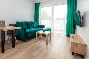 Apartamenty Przy IV Śluzie - Green في بيدغوشتش: غرفة معيشة مع أريكة خضراء وطاولة