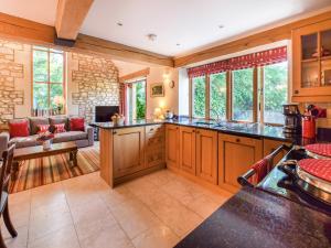 a kitchen with wooden cabinets and a living room at The Stables, Batheaston in Batheaston