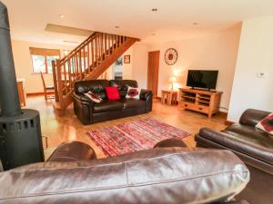 a living room with a leather couch and a tv at Grange View in Ripon