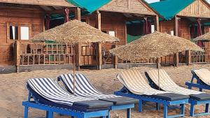 a group of chairs and umbrellas on a beach at Saxony Beach Huts in Agonda